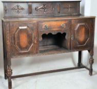 A 1930's large oak jacobean revival sideboard raised on cup and cover legs united by stretchers