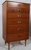 A retro 1970's teak and rosewood effect upright chest of drawers. Raised on turned legs having a