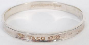 A silver 925 white metal ladies bracelet by Tiffany & Co. The plain bangle being stamped to front