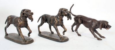 Three 20th century cast metal studies of gun dogs. Two being a pair (with fowl in mouths) and the