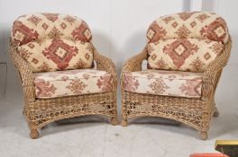 A pair of good quality wicker conservatory armchairs having contemporary fabric covered cushions.
