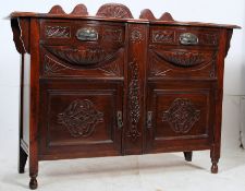 An Edwardian mahogany breakfront sideboard having carved centre over a series of drawers and