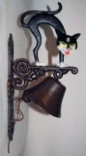 A 20th century cast metal wall hanging bell with cat casting to top. Handpainted decoration. 39cm