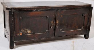 A Jacobean style low cabinet having twin doors with flared top raised on square legs