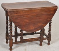 A 1930's oak barleytwist drop leaf dining table having gate legs with swing action supporting the