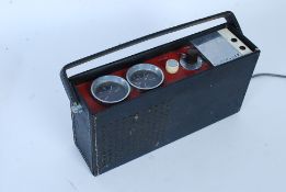 A vintage Ferguson transistor portable radio with decorative facia atop set within a vinyl