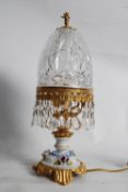 A decorative crystal glass and china gilt effect table lamp, with hanging droplets to edge of