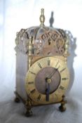 A small decorative 20th century brass lantern clock with pierced fret decoration atop.