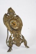 A brass Edwardian rococo easel timepiece clock. The rococo brass easel with folding support housing