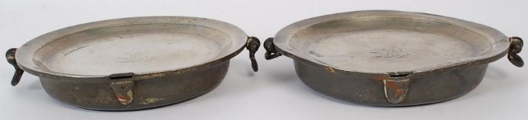 A pair of 19th century pewter plate warmers bearing illegible touch marks having armorial crests to