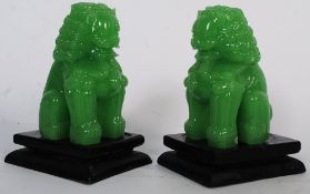 Two Chinese oriental glass temple lions on ebonised wooden plinths.