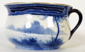 A Royal Doulton blue and white china potty with forest transfer scene and gilt effect handle.