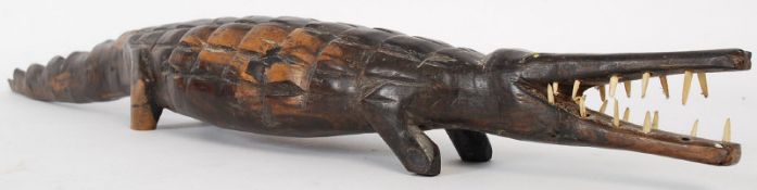 An unusual early 20th century tribal art wood figure of a crocodile having bone teeth.