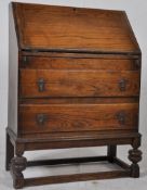 A 1930`s oak bureau bookcase being raised on cup and cover legs having fall front with drawers to