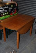 A large retro 1970`s oak drop leaf dining table raised on angular tapered legs