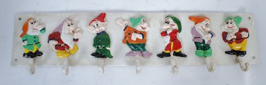 A cast iron childs cup / coat rack, featuring the 7 Dwarves from Disney`s Snow White & The Seven