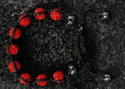 A ladies shambala bracelet with red colour decoration.