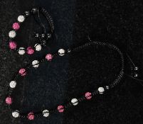 A shambala crystal necklace with pink and white toned decoration in alternate colouring.