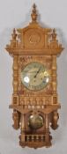 A 20th century German black forest 8 day wall clock with decorative case having inset brass face and