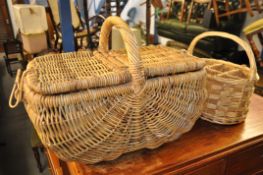 A wicker picnic hamper with another wicker basket and a small plant stand.