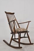 A Ercol beech and elm rocking chair on turned legs united by stretchers supporting an elm seat