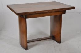 A 1930's walnut Art Deco draw leaf refectory dining table. Bow supports united by stretcher having
