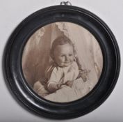 An Edwardian ebonised porthole photoframe. The inset photo of baby. The verso dated to 1901 with