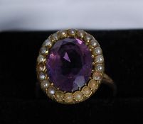 A 9ct gold ring with seed pearl surround, around a purple inset stone. 4.5g