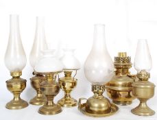A collection of Victorian and later brass oil lamps complete with glass chimneys and shades ( see