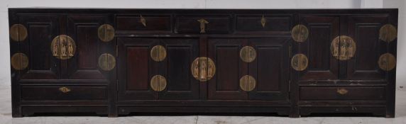 A large 20th century Chinese low cabinet constructed of heavy solid hardwood being raised on style