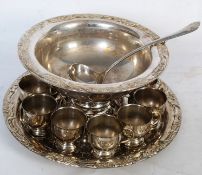 A large ecclesiastical style silver plate punch bowl, cups and tray with chased decoration to