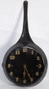 A vintage kitchen clock in frying pan form with affixed brass numerals to dial.