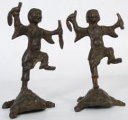 A pair of 19th century bronze Chinese figurines. The figures with weapons to each hand, raised on