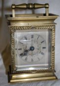 A small 20th century brass carriage clock with a silvered dial and glass viewing apertures to