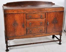 A 1920`s carved oak sideboard having large doors having inset metal storage flanking a central bank