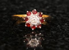 A ruby and diamond 18ct solitaire ring. Flowerhead design. 8 ruby stones with a central diamond in