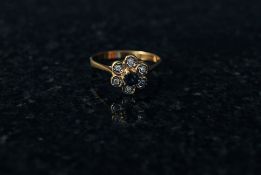 A 9ct gold sapphire and diamond daisy ring. The centre set sapphire bearing diamonds to each of the