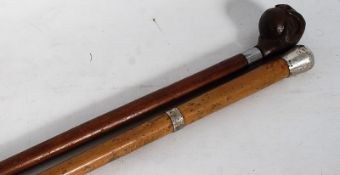 A silver topped walking stick cane along with a ball and hand topped carved wood walking stick