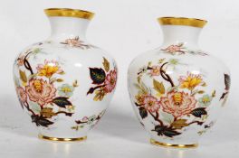 A KPM Bavarian pair of hand painted porcelain vases with gilt and flower decoration. 13cm tall.