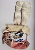 2 sets of cricket pads together with cricket gloves in a sports bag. One set by Crusader