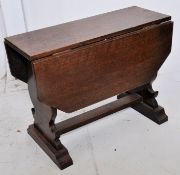 An early 20th century solid oak drop leaf dwarf occasional table. The shaped supports to the