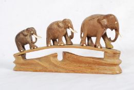 A hardwood African carved set of 3 graduating elephants on plinth. With inlaid bone tusks and eyes