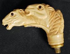 A carved bone walking stick handle in the form of three horses heads.