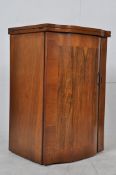 A 1930`s Art Deco burr walnut sewing table cabinet. The bow front door having flip over top with