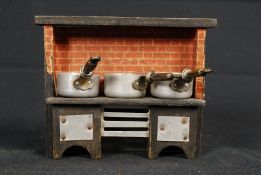 An early 20th century dolls house range cooker complete with 3 french metal saucepans. 13cm tall.