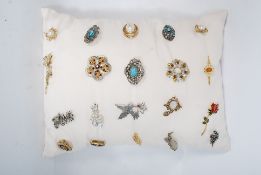 20 costume brooches on a display cusion to include glass, stone and enamel examples.