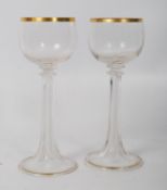 A pair of Victorian cut glass fluted wine goblets with gilt decoration having hollow stems. 19cm