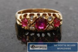 An 18ct gold ruby and diamond  ring. The 3 centre ruby`s surrounded by diamonds to the fret pierced