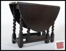 A Jacobean revival oak drop leaf dwarf occasional table. The barley twist legs united by stretchers