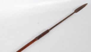 An African tribal spear. The carved and polished shaft having a bound short arrow head on long